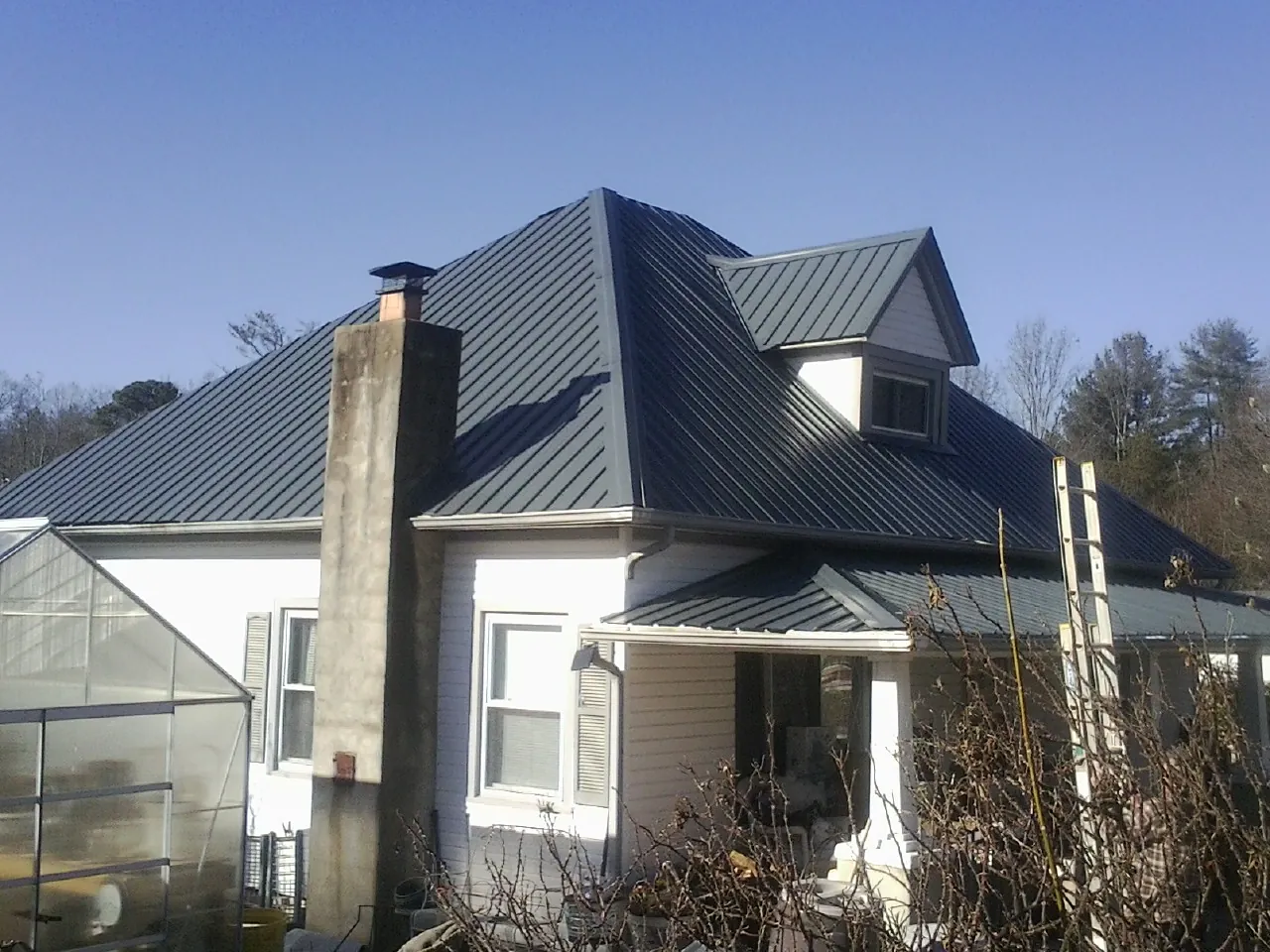 Dark blue standing seam metal roof on a white farmhouse with dormer — Slate & Tile Roof Repair by Roofing Brothers in Grand Island