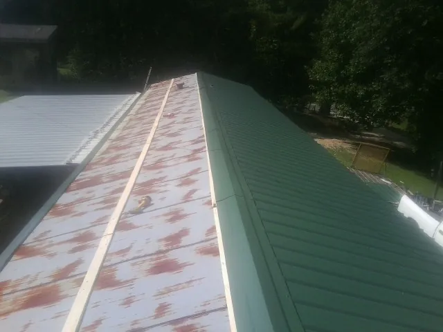 Old rusted panels beside newly installed green metal roofing — Wind Damage Roof Repair by Roofing Brothers in Grand Island