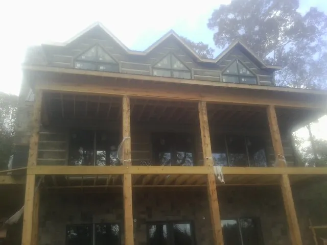 Dormers and porch framing on a large log home under construction — Roof Coating work by our crew in Grand Island