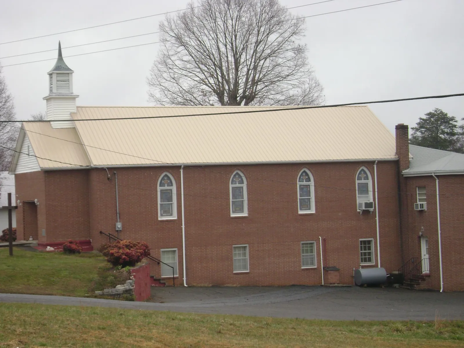 New tan metal roof on a brick church with a white steeple in Grand Island